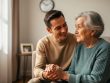 “Caregiver holding the hand of an elderly parent in a softly lit living room near a window, representing Alzheimer’s support and compassionate home care.”